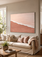 Blush pink coastal wall art displayed above a cream sofa in a soft contemporary living room