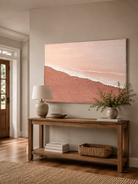 Minimalist blush pink beach painting displayed above a wood console in a modern neutral entryway