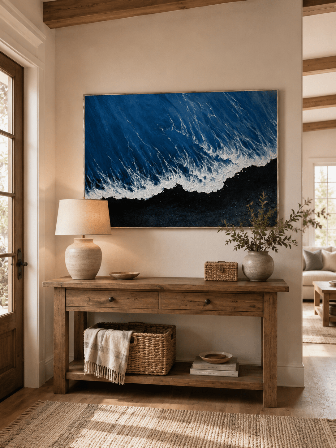 Modern blue and black ocean painting displayed above a wide wood console in a contemporary entryway