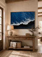 Modern blue and black ocean painting displayed above a wide wood console in a contemporary entryway