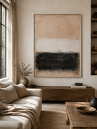 Beige and black abstract painting displayed above neutral furniture in an organic modern living room