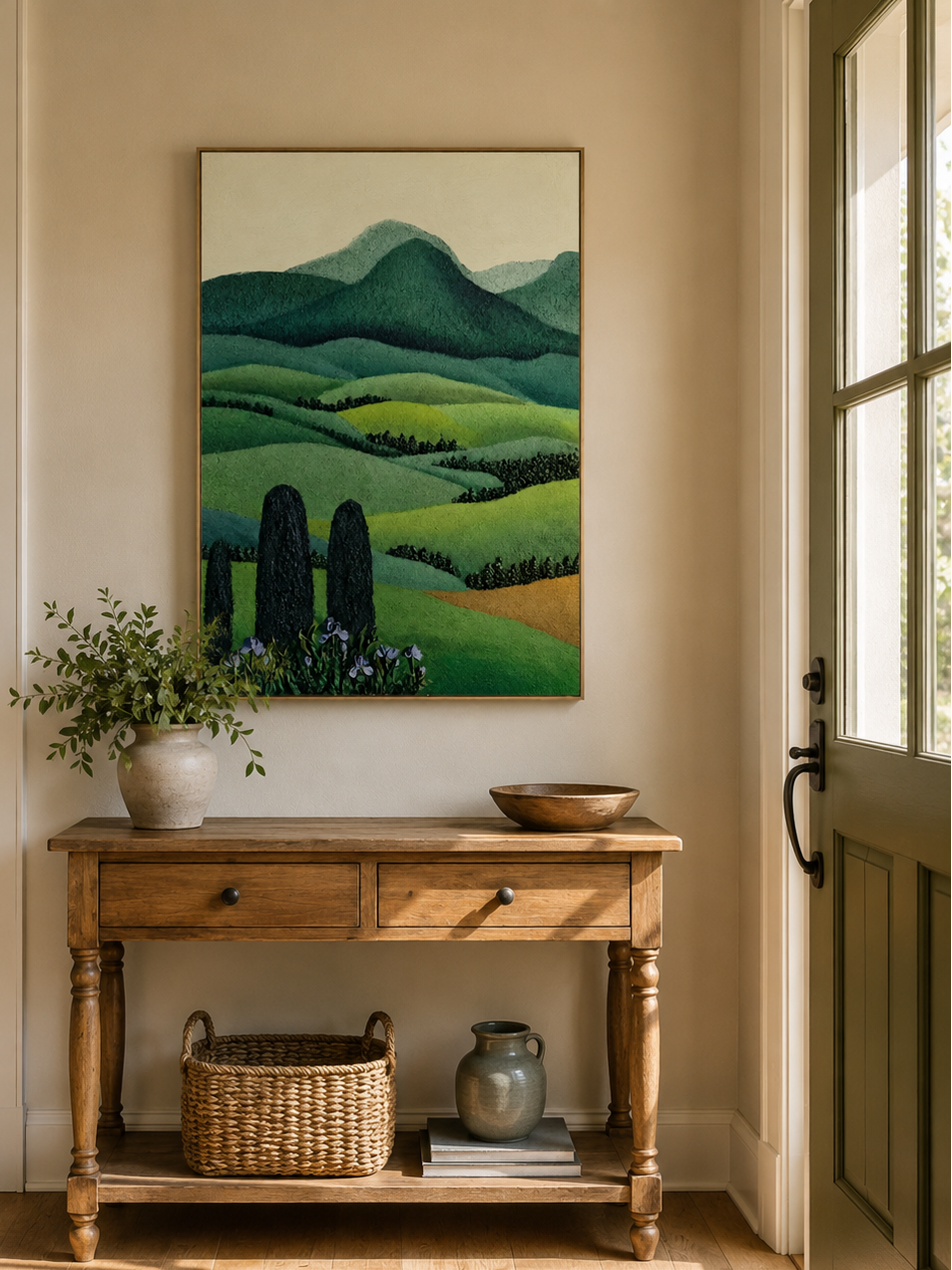 Rolling hills and cypress tree painting displayed above a wood console in a warm modern entryway