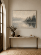 Horizontal misty lake painting displayed above a long wood console in a warm modern entryway