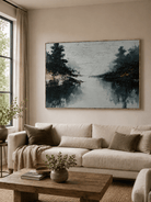 Moody lake reflection painting displayed above a neutral sofa in an organic modern living room