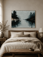 Neutral gray-blue lake landscape displayed above the bed in a calm minimalist bedroom