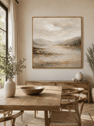 Large textured mountain lake painting with beige and gold tones displayed in a modern open dining room