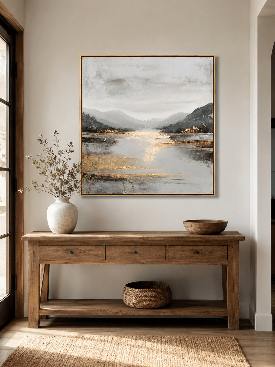 Gray and gold mountain lake wall art displayed above an entryway console in a contemporary neutral home