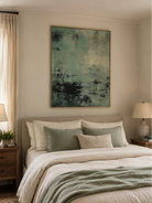 Wabi-sabi green abstract painting displayed above a bed in a calm modern bedroom