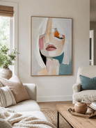 Abstract feminine portrait painting above a neutral sofa in a soft modern living room