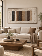 Large horizontal brown and beige textured wall art displayed above a cream sofa in an organic modern living room