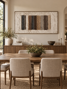 Large horizontal textured geometric wall art displayed in an open dining room with walnut and stone furniture