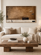 Large brown horizontal abstract wall art displayed above a cream sofa in an organic modern living room