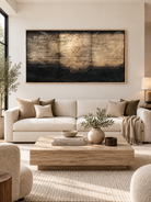 Large black and gold-toned horizontal abstract wall art displayed above a cream sofa in a modern living room