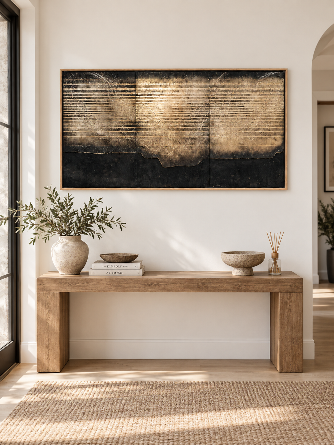 Extra wide black and gold-toned abstract wall art displayed above a long entryway console in an organic modern interior