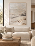 Large neutral textured abstract landscape painting displayed above a modern living room sofa in a minimalist interior