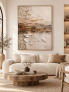 Large earth tone textured abstract landscape painting displayed above a sofa in a modern organic living room