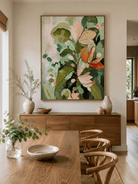 Large abstract botanical wall art with green foliage and warm coral flowers displayed in an open dining room