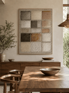 Neutral geometric relief wall art displayed in an organic modern open dining room with wood and stone furniture