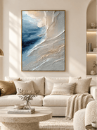 Large blue gray textured ocean wall art displayed above a sofa in a contemporary coastal living room