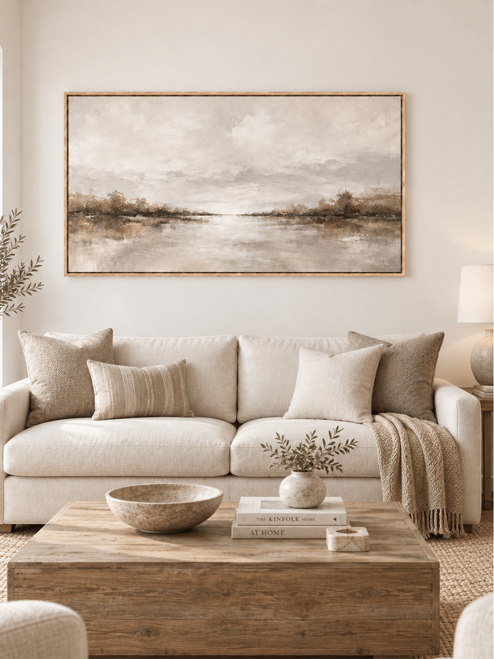 Large neutral panoramic lake landscape painting displayed above a sofa in a modern organic living room