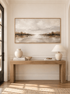 Wide panoramic lake landscape painting displayed above a long console in a contemporary entryway