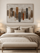 Neutral abstract columns painting in beige, brown and charcoal displayed above a bed in a minimalist bedroom