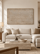 Large neutral textured abstract wall art with raised ivory dots displayed above a sofa in a modern organic living room