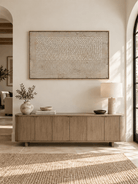 Horizontal neutral abstract painting with raised dot texture displayed above a console in a minimalist entryway