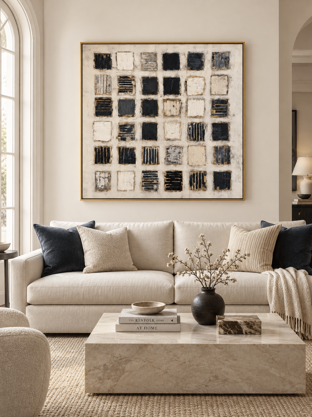Large black and white geometric abstract painting displayed above a cream sofa in a contemporary living room