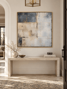 Horizontal blue gray textured abstract painting with subtle golden details displayed above an entryway console