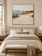 Soft pink and sage green meadow painting displayed above a bed in a warm minimalist bedroom