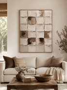 Large neutral textured geometric wall art displayed above a beige sofa in an organic modern living room