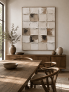 Neutral geometric textured wall art displayed in an organic modern open dining room with wood and stone furniture