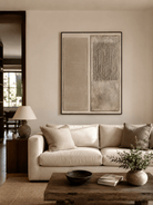 Large neutral textured wall art displayed above a beige sofa in a minimalist organic modern living room
