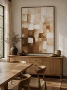 Large earth tone geometric wall art displayed in an organic modern open dining room with wood and stone furniture