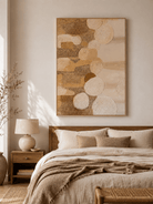 Neutral wabi-sabi abstract wall art with sculptural circles displayed above the bed in a warm minimalist bedroom