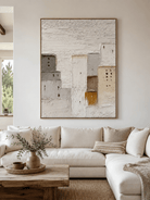 Large neutral textured architectural wall art displayed above a beige sofa in an organic modern living room