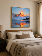 Blue and orange alpine mountain wall art displayed above a bed in a calm modern bedroom