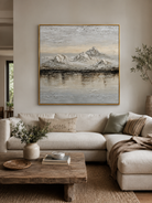 Neutral textured mountain lake painting above a cream sofa in an organic modern living room