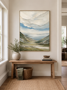 Textured mountain landscape wall art above an entryway console in an organic modern foyer