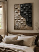 3D pebble wall art displayed above a bed in a warm neutral contemporary bedroom