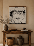 Black and white expressionist face wall art above a console in a modern entryway