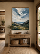 Coastal landscape wall art above an entryway console in an organic modern foyer