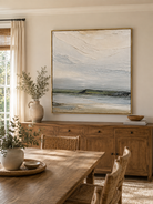 Hand-painted textured coastal landscape wall art displayed in a modern open-plan dining room with natural wood decor