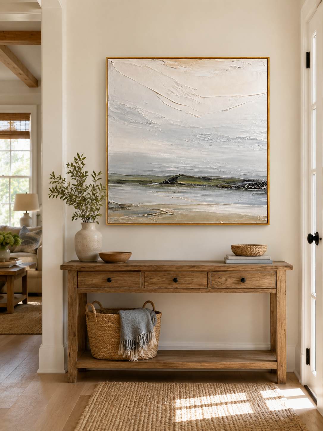 Neutral coastal landscape painting displayed above a wood console in a minimalist organic modern entryway