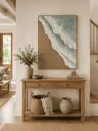 Vertical sage green beach wave painting displayed above a wood console in a minimalist modern entryway