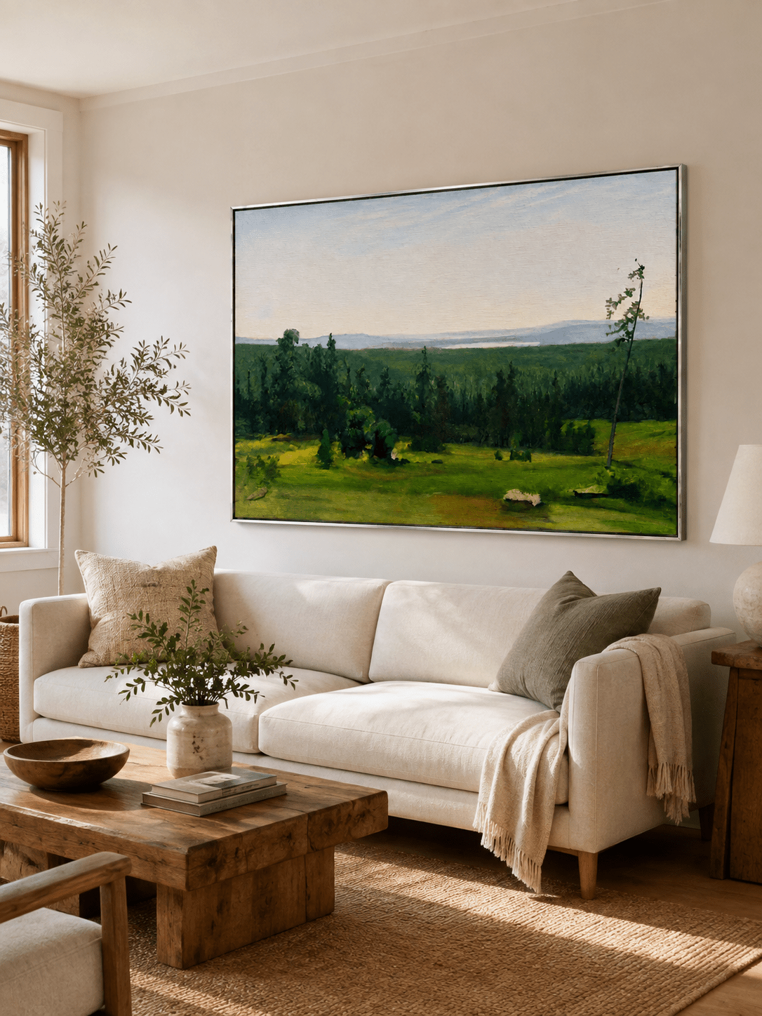 Green meadow landscape painting displayed above a neutral sofa in an organic modern living room