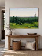 Horizontal green meadow painting displayed above a long wood console in a modern entryway