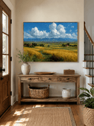 Horizontal golden field landscape painting displayed above a wood console in a modern entryway