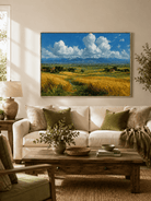 Golden wheat field landscape painting displayed above a neutral sofa in a modern living room